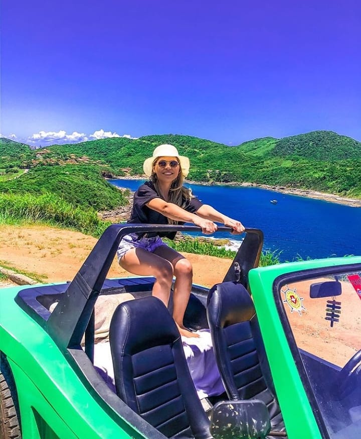 Mujer con sombrero en un buggy verde disfrutando de un mirador en Búzios