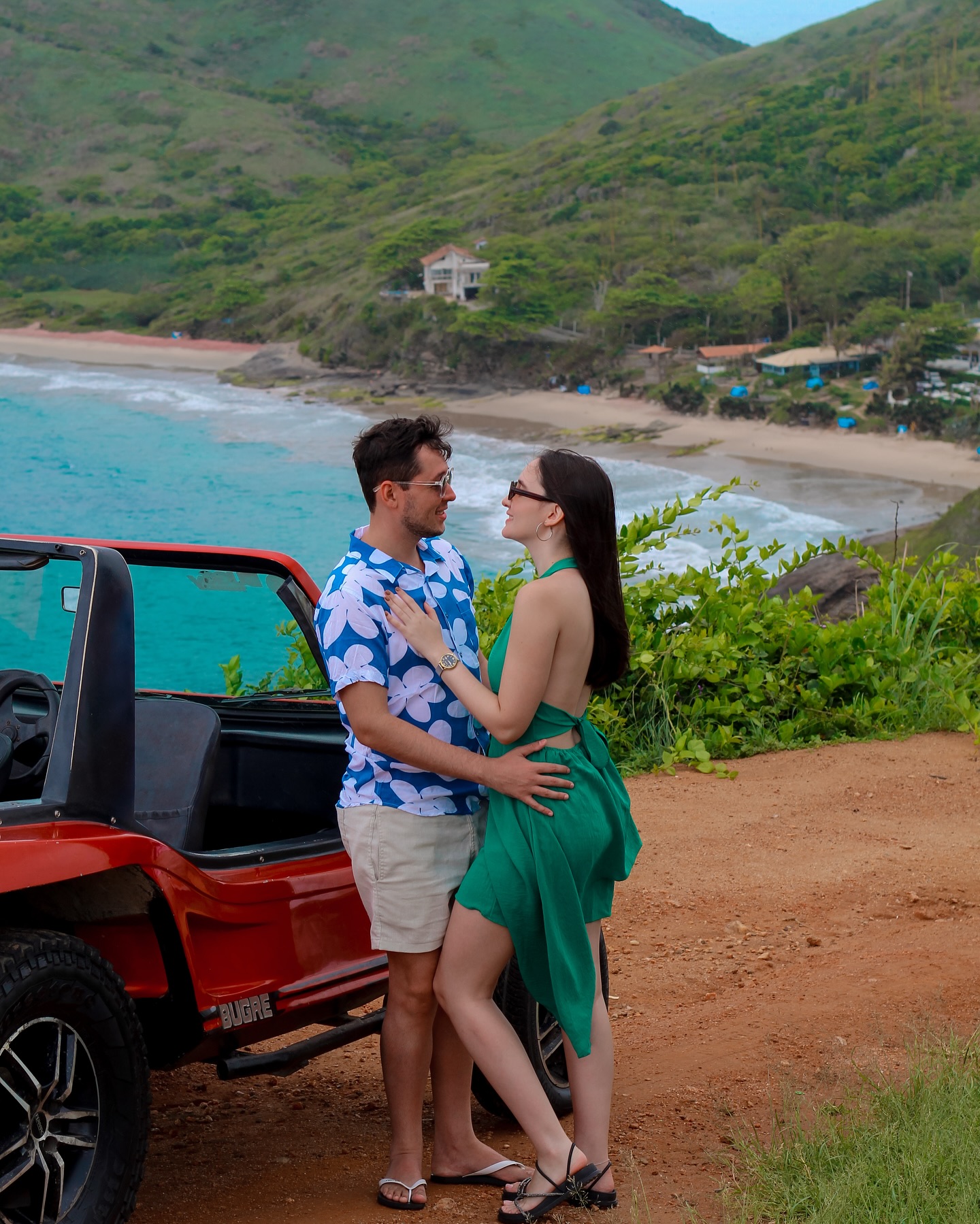 Pareja junto a un buggy rojo en un mirador sobre una playa de Búzios